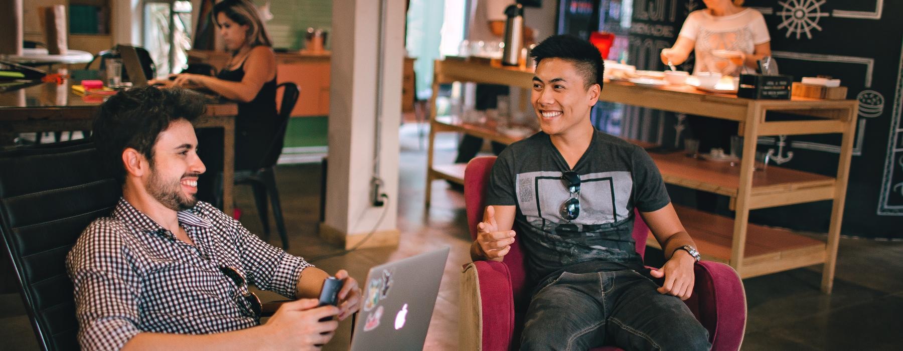 a couple of men sitting in chairs with laptops