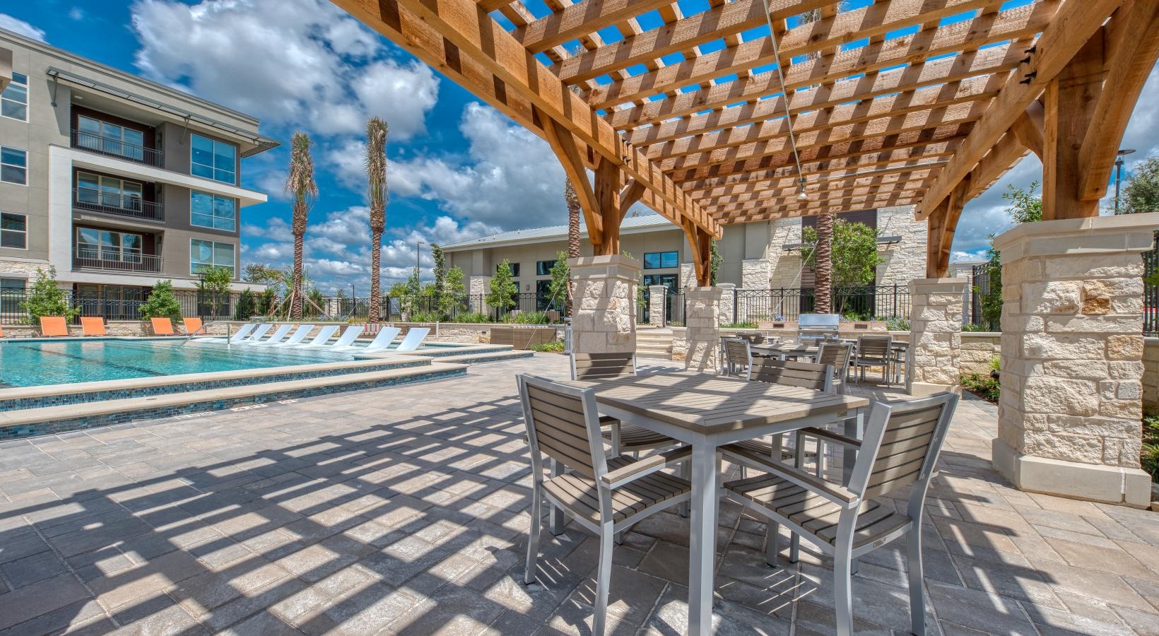 Relax and unwind poolside a table and chairs next to a pool