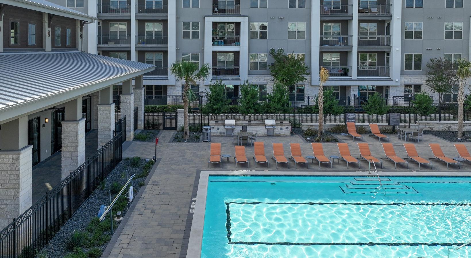 Relax and unwind poolside a swimming pool in front of a building